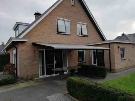 Knikarmscherm boven een terras bij een woning